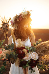 Amazing bride in sunset light. Pretty bride. Boho style. Bride wearing fashion wedding dress with feathers with luxury delight make-up and hairstyle