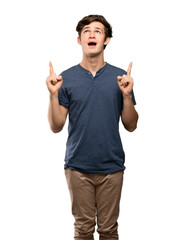 Teenager man pointing up and surprised over isolated white background