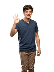 Fototapeta premium Teenager man showing ok sign with fingers over isolated white background