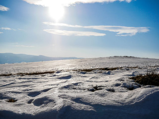 Frozen snow on the top of the hill , visible sun on blue sky.