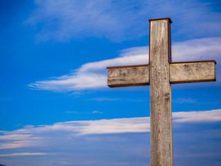 Simple wood catholic cross, blue sky with white clouds background, copy space.