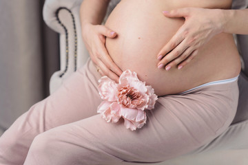 Lovely hands of pretty beautiful young pregnant woman in sportswear at home. Waiting for a baby future mother concept