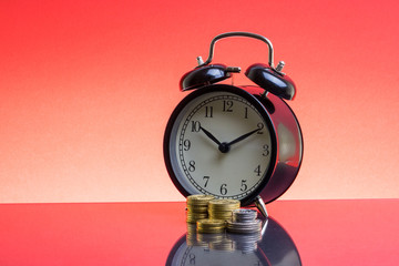 Alarm Clock and coins on red background with selective focus and crop fragment. Copy space  and business concept