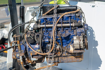 blue engine block being lifted from boat by pulley and chain using lifting equipment
