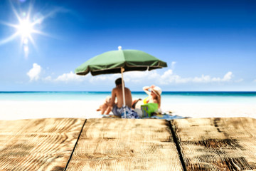 Desk of free space for your product. Beach landscape with people on towel. Ocean water and sun light