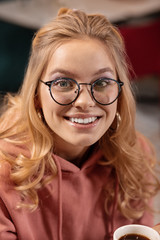 Obraz premium Close up portrait of young Caucasian woman looking through the camera and smiling beamingly.