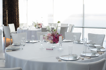 Event white restaurant table served and decorated with delicate fresh flowers