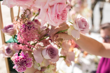 florist decorator workflow, Woman hands decorating wedding arch with fresh flowers. Event decoration with fresh flowers