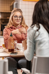 Attractive girl listening to her friend while having lunch.