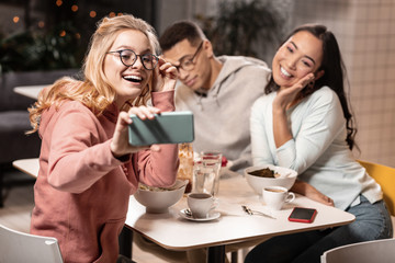 While guy feeling headache, his friends taking photos with each other.