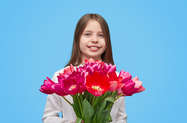 Cute girl with pink tulips on blue backdrop 