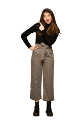 Full-length shot of Pretty girl surprised and pointing side on isolated white background