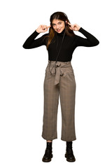 Full-length shot of Pretty girl listening to music with headphones on isolated white background