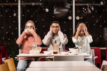 Three students preparing for theatrical production while doing their rehearsal in cafe.