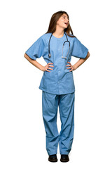 Full-length shot of Young nurse posing with arms at hip and laughing on isolated white background