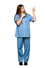 Full-length shot of Young nurse pointing with the index finger and looking up on isolated white background