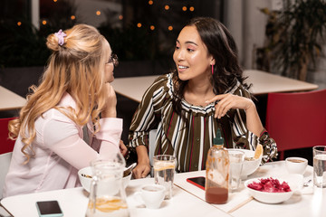 While talking girls sitting up late in Asian cafe.