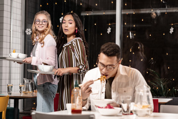 Two girls passing be boy and evaluating his skills of using chopsticks.