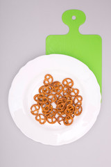 Pretzel on a white plate with a kitchen board, top view