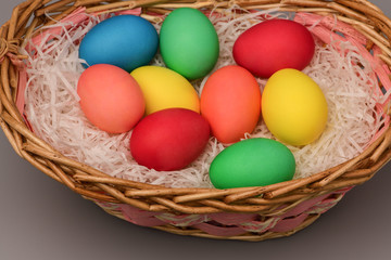 Fototapeta na wymiar Top view of Easter colorful eggs in basket on grey background