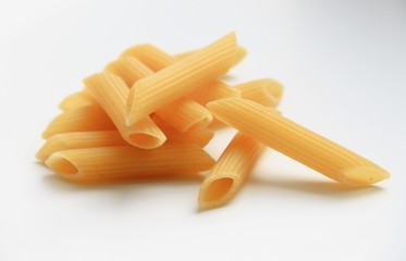 Yellow uncooked pasta are on a white background.