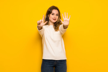Teenager girl over yellow wall counting seven with fingers