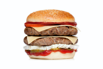 Juicy burger with two cutlets, cheese, cucumber, tomato, onion, cabbage, sauce and sesame bun on a white background