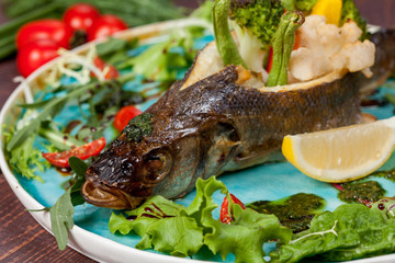  appetizing fried fish, beautifully laid out with greens and vegetables on a dish, for designer solutions in cooking