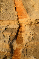 Cracked surface of a clay slope. The cracks have allowed access of oxygen, so the ferrous soil has oxidated along the cracks.