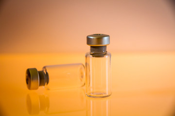 two vaccine bottles on orange background
