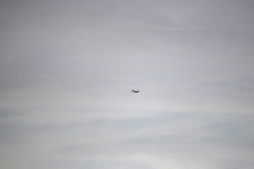 Silhouette of plane flying through the cloudy sky