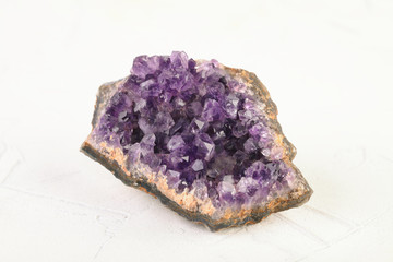 Beautiful amethyst druse close-up on white cement background. Semi precious gem used for jewels.