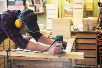 Worker grinds the wood box of angular grinding machine. Profession, carpentry and woodwork concept.