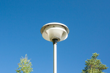 Street lamp and trees on clear sky background.