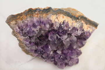Beautiful amethyst druse close-up on white cement background. Semi precious gem used for jewels.