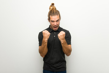 Blond man with long hair over white wall frustrated by a bad situation