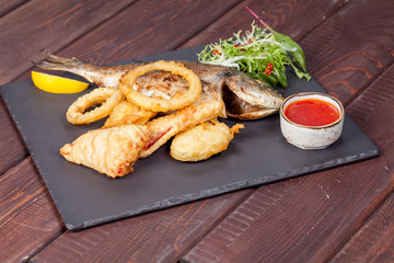  appetizing fried fish, beautifully laid out with greens and vegetables on a dish, for designer solutions in cooking
