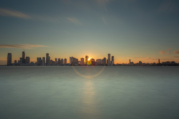 Fototapeta premium View on Jersey city with direct sun from hudson river with long exposure