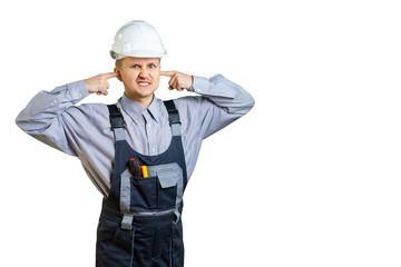 The builder in overalls and a protective helmet covers his ears with his hands. It is unbearable to hear the opinion of the customer about the work done. Isolated.