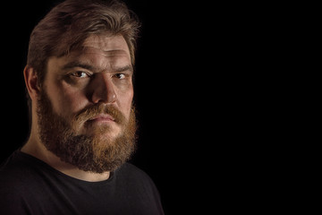 Close-up portrait strong serious brutal bearded man on black. Confident and dramatic concept