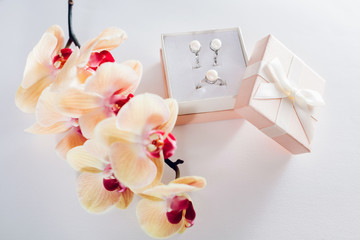 Obraz na płótnie Canvas Gift box with a set of perl jewellery surrounded with orchid. Present for Women's day