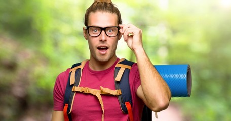 Hiker man with mountain backpacker with glasses and surprised in the mountain