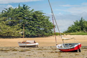 Small sail boats stranded and grounded on the beach in Brittany