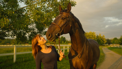 Obraz premium CLOSE UP: Caring Caucasian girl lovingly looking at her muscular brown stallion.