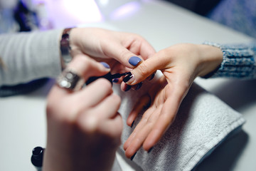 woman in a nail salon receiving a manicure nail gel polish by a professional beautician