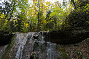 Waterfall in the autumn forest on the mountainside.