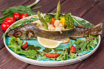  appetizing fried fish, beautifully laid out with greens and vegetables on a dish, for designer solutions in cooking
