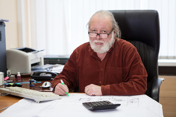 Architectural engineer working with blueprints and documents, writing on drawings. An architect...