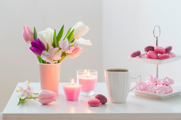 Tulips in vase and cup of coffee with dessert on white background. Concept woman's or mother's day