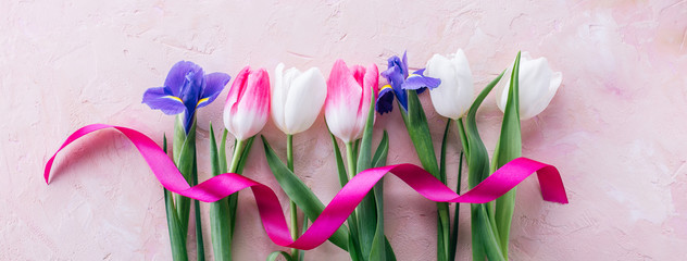 Tulips and irises with a pink satin ribbon on a pink background